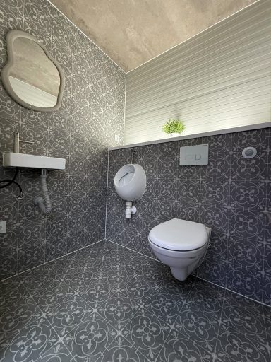 Innenansicht Herrenbereich mit Urinal, WC und Waschbecken in modernem Design